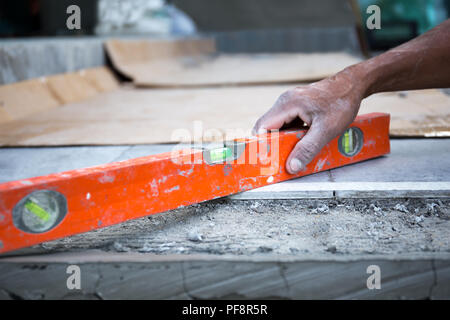 Äußere Arbeiter mit Niveau für die Verlegung von Estrich Stockfoto