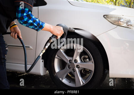 Mann Reinigung ein Auto mit Hochdruck reinigen Stockfoto