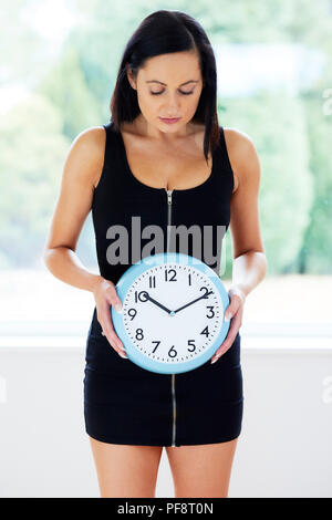 Frau stand hielt eine Uhr Stockfoto