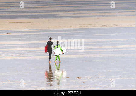 Vater und Sohn Anzüge tragen und Durchführung body Boards zu Fuß auf den Fistral Beach in Cornwall. Stockfoto