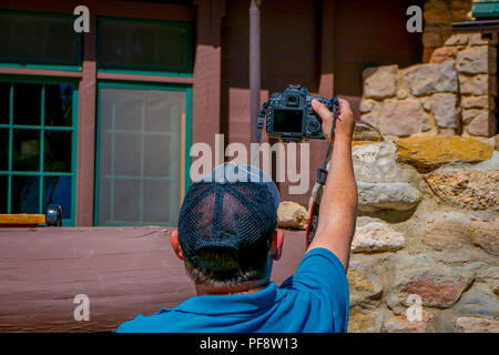 BRYCE Canyon, Utah, Juni, 07, 2018: Mann mit dem schwarzen Hut und blaue T-Shirt Strecken des Armes ein Bild von einem schönen goldenen-mantled ground squirrel in Bryce Canyon National Park, Utah zu nehmen Stockfoto