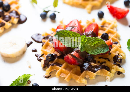 Waffeln mit frischen Erdbeeren und Schokolade Topping. Süße Nachspeise auf weißem Hintergrund. Close Up. Stockfoto