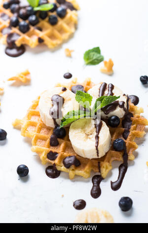 Waffeln mit frischen Heidelbeeren und Banane und Schokolade Topping. Süße Nachspeise auf weißem Hintergrund. Close Up. Stockfoto