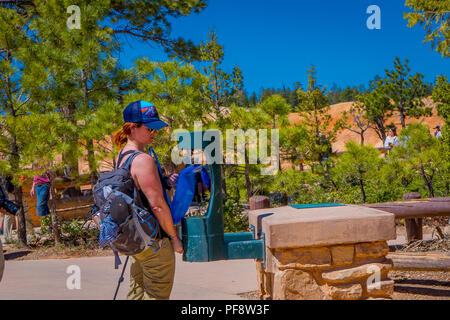 BRYCE Canyon, Utah, Juni, 07, 2018: Nicht identifizierte Frau mit Hut und bequeme Kleidung, ihre blauen Kunststoff Thermoskanne Befüllen in einem Wasser nachfüllen für eine Reise rund um den Bryce Canyon National Park, Utah Stockfoto