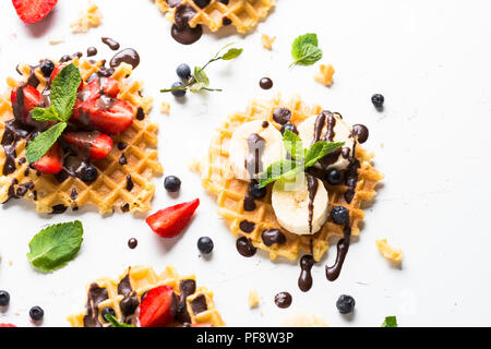 Waffeln mit frischen Beeren - Erdbeere, Heidelbeere, Bananen und Schokolade Topping. Süße Nachspeise auf weißem Hintergrund. Close Up. Stockfoto