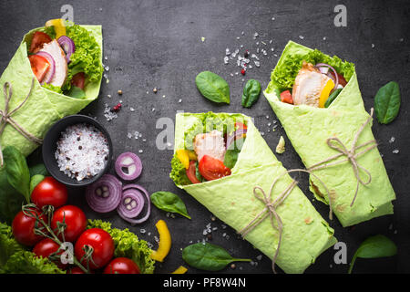 Grüne Spinat Tortilla mit Hähnchen und Gemüse. Ansicht von oben mit der Kopie auf schwarzem Schiefer Tisch. Gesunden Snack. Stockfoto