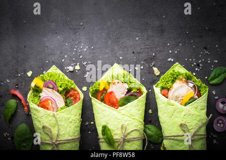 Grüne Spinat Tortilla mit Hähnchen und Gemüse. Draufsicht auf schwarzem Schiefer Tisch mit kopieren. Gesunden Snack. Stockfoto