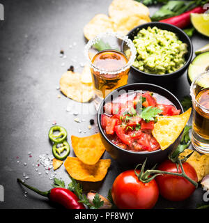 Lateinamerikanische mexikanisches Essen party Soße Guacamole, Salsa, Chips und Tequila auf Schwarz. Stockfoto