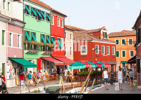 Sonnenuntergang in der farbenfrohen Fischerdorf auf der Insel Burano, Venedig, Venetien, Italien, Open air Restaurant, Sonnenschirme, canal Szene, Leute, Touristen, Stockfoto