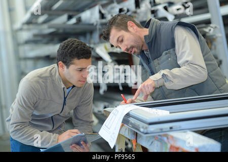 männlichen Vorgesetzten mit Arbeiter diskutieren über Baupläne in der Industrie Stockfoto