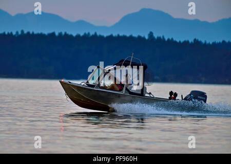 Ein horizontales Bild eines sich schnell bewegenden Motorboot entlang des Wassers im Abendlicht unterwegs Auf der Straße von Georgia in der Nähe von Vancouver Island British Colum Stockfoto