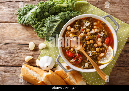 Suppe mit Kichererbsen, Grünkohl, Tomaten, Knoblauch und Kartoffeln mit Zitrone schließen in einer Schüssel auf dem Tisch. horizontal oben Ansicht von oben Stockfoto