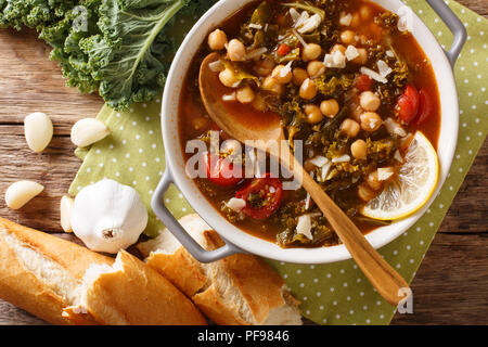 Gemüse Eintopf aus Kichererbsen, Grünkohl, Tomaten, Knoblauch und Kartoffeln mit Zitrone schließen in einer Schüssel auf dem Tisch. Horizontal oben Ansicht von oben Stockfoto