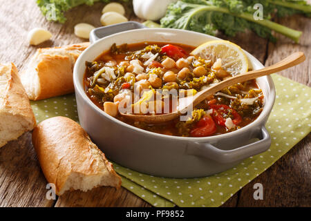 Suppe mit Kichererbsen, Grünkohl, Tomaten, Knoblauch und Kartoffeln mit Zitrone schließen in einer Schüssel auf dem Tisch. Horizontale Stockfoto