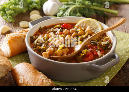 Gemüse Eintopf aus Kichererbsen, Grünkohl, Tomaten, Knoblauch und Kartoffeln mit Zitrone schließen in einer Schüssel auf dem Tisch. Horizontale Stockfoto