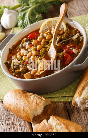 Gemüsesuppe mit Kichererbsen, Grünkohl, Tomaten, Knoblauch und Kartoffeln in der Nähe in einer Schüssel auf dem Tisch. Vertikale Stockfoto