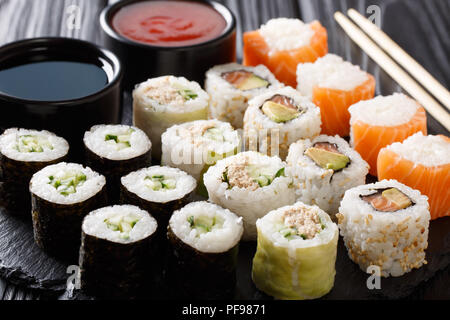 Menü Einstellen des Japanischen Brötchen mit Lachs, Thunfisch, Avocado, Gurke mit Soßen serviert schließen - bis auf einen Stein board. Horizontale Stockfoto