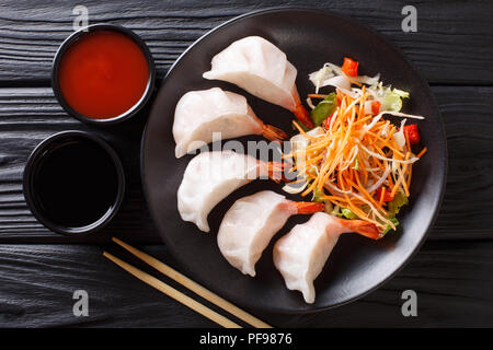 Chinesische Knödel jiaozi mit Garnelen mit Salat in der Nähe serviert auf einem Teller. horizontal oben Ansicht von oben Stockfoto