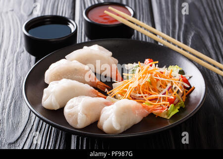 Jiaozi, Gyoza-teigtaschen mit Garnelen close-up mit Gemüse und Soja und Tomatensauce auf den Tisch serviert. Horizontale Stockfoto