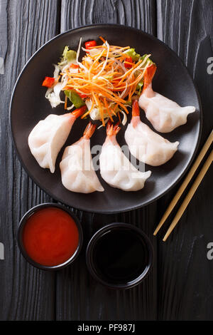 Chinesische Knödel jiaozi mit Garnelen mit Salat in der Nähe serviert auf einem Teller. Vertikal oben Ansicht von oben Stockfoto