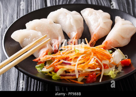 Chinesische Knödel jiaozi mit Garnelen mit Salat in der Nähe serviert auf einem Teller. Horizontale Stockfoto