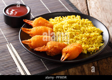 Teil der Krabben gebraten in Panade mit Reis und Tomatensoße in der Nähe serviert auf einem Teller auf dem Tisch. Horizontale Stockfoto