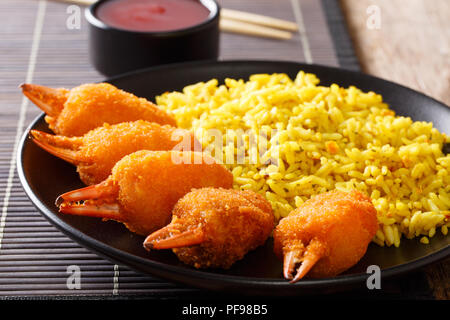 Fried Crab Claws in Paniermehl mit würzigen gelber Reis close-up auf einem Teller auf dem Tisch. Horizontale Stockfoto