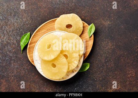 Getrocknete Ananas Ringe auf einem braunen Tisch. Top viw Süße paneapple Schichten. Stockfoto