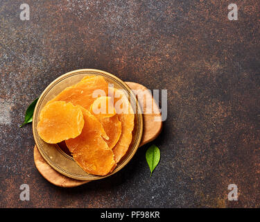 Getrocknete mango Slices. Draufsicht der kandierten Früchte auf braunem Hintergrund. Stockfoto