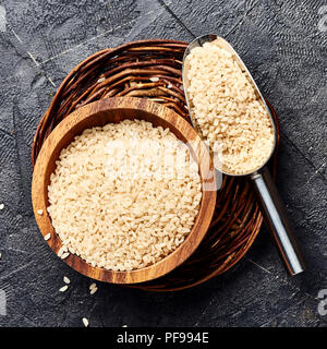 Weißer Reis in Houten auf schwarzem Hintergrund. Draufsicht der Körner. Stockfoto