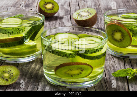 Natürliche selbstgemachte Getränke für das verlieren Bauch Fett mit in Scheiben geschnittenen Kalk, Kiwi, Gurke und Minze in den drei Gläser, close-up Stockfoto