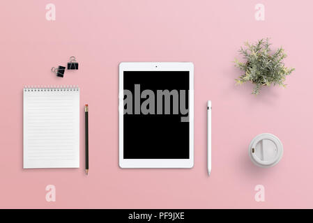 Weibliche Arbeit Tabelle mit einer Tablette. Leerer Bildschirm für mockup. Rosa Oberfläche. Flach, Ansicht von oben. Stockfoto