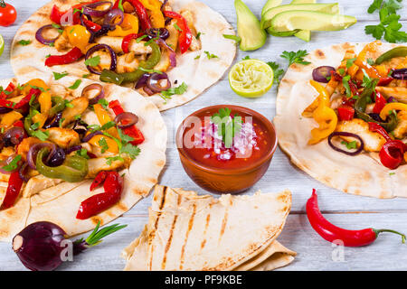 Hausgemachte chicken Burritos mit Gemüse, Kalk und Salsa Soße auf weißen Hintergrund Holz, voll konzentrieren, Studio leuchten, Nahaufnahme, Ansicht von oben Stockfoto