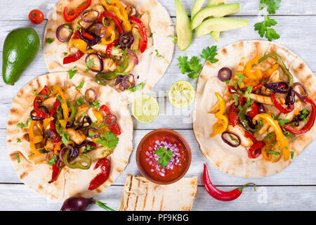 Hausgemachte Chicken Fajitas mit Gemüse, Kalk und Salsa Soße auf Holz- Hintergrund, voller Fokus, Studio leuchten, Ansicht von oben Stockfoto