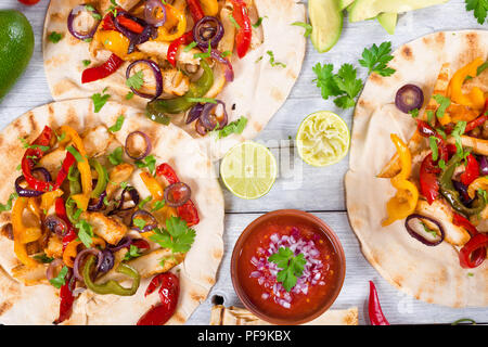 Hausgemachte Chicken Fajitas mit Gemüse, Kalk und Salsa Soße auf Holz- Hintergrund, voller Fokus, Studio leuchten, Ansicht von oben Stockfoto