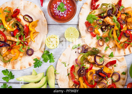 Hausgemachte Chicken Fajitas mit Gemüse, Kalk und Salsa Soße auf Holz- Hintergrund, voller Fokus, Studio leuchten, Ansicht von oben Stockfoto