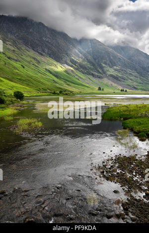 Loch Achtriochtan auf dem Fluss Coe mit dappled Sonne auf den steilen Aonach Eagach Ridge Berge in Wolken Glen Coe Tal Schottland Stockfoto