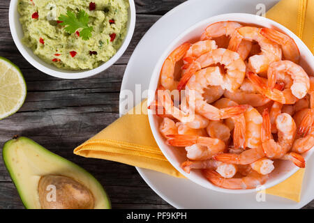 Garnelen auf einem weißen Teller mit Guacamole Sauce in einer Schüssel auf einem alten rustikalen Tabelle, Ansicht von oben Stockfoto