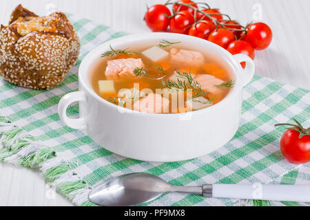 Lachs Suppe mit Karotte und Kartoffel, gewürzt mit Dill in Weiß Schüssel auf der karierten Tabelle Serviette begleitet mit Käse Brötchen und Cherry tomat Stockfoto