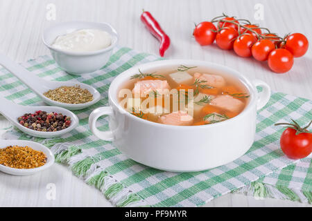 Lachs Suppe mit Karotte und Kartoffel, gewürzt mit Dill in Weiß Schüssel auf einem weißen Tisch, mit Sahne und Gewürzen, close-up Stockfoto