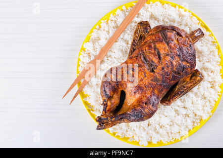 Gebratene ganze Ente in Honig Senf Soja Glasur auf einem gelb Gericht mit auf einem weißen Hintergrund, Ansicht von oben Stockfoto