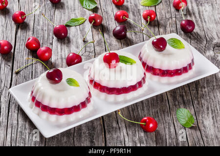 Italienische Dessert von kirschsaft und gesüßte Sahne verdickt mit Gelatine und geformt und auf eine rechteckige Schale mit Kirschen auf einem dunklen Holz- backgro Stockfoto