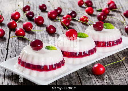 Italienische Dessert von kirschsaft und gesüßte Sahne verdickt mit Gelatine und geformt und auf eine rechteckige Schale mit Kirschen auf einem dunklen Holz- backgro Stockfoto