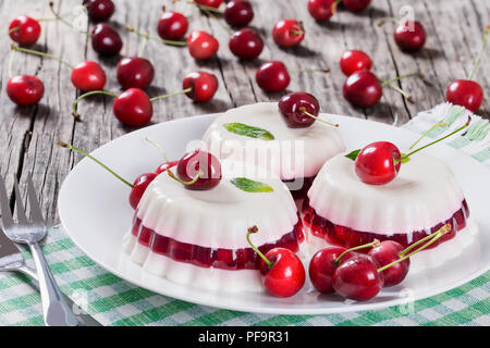 Italienische Dessert von kirschsaft und gesüßte Sahne verdickt mit Gelatine und geformt, auf einem weißen Teller auf einen Tisch Serviette mit Dessert Gabeln und Mellie Stockfoto