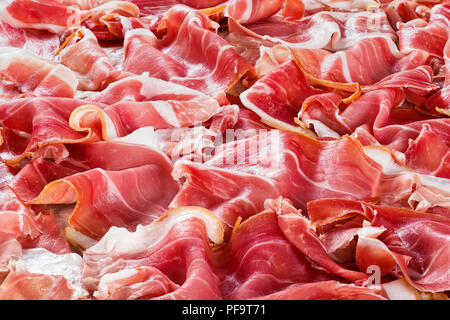 Gerollte Scheiben köstliche italienische Prosciutto auf Pergamentpapier auf alten rustikalen Tabelle, Ansicht von oben Stockfoto