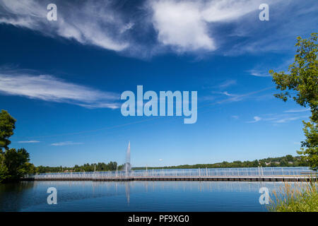 Die schwimmende Fußgänger- und Fahrrad Brücke über die Mündung des Flusses Yamaska vom Lac Boivin. Der Springbrunnen im Hintergrund. Granby, östlichen Townsh Stockfoto