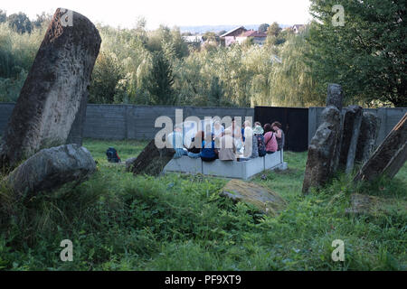 Die Teilnehmer der ROOTKA-Reiseagentur, die sich auf jüdische Kulturreisen in Osteuropa spezialisiert hat, sitzen inmitten alter Grabsteine auf dem verlassenen jüdischen Friedhof mit fast 3000 Grabsteinen in den Vororten von Bolechiv, einer regionalen Stadt im Gebiet Ivano-Frankiwsk (Provinz) der Ukraine, in der einst eine große jüdische Gemeinde beheimatet war. Während des Holocaust wurde die jüdische Gemeinde von den Deutschen mit lokalen ukrainischen Kollaborateuren brutal vernichtet. Stockfoto