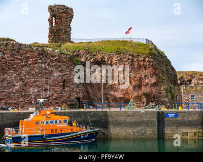 RNLI Lifeboat vertäut im Hafen, mit ruiniert Dunbar Castle, Dunbar, East Lothian, Schottland, Großbritannien Stockfoto