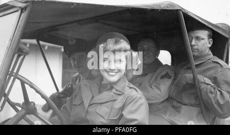 Schwarz-weiß Foto, zeigt eine Nahaufnahme eines jungen, weiblichen Fahrer, der in die Kamera lächelt, mit mehreren männlichen Passagiere in Ihrem Fahrzeug sitzen, alle vier in Militäruniformen, wahrscheinlich in Ohio während des Zweiten Weltkrieges, 1945 fotografiert gekleidet. () Stockfoto