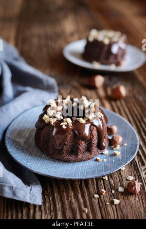 Mini Schokolade bundt Kuchen mit Glasur und gehackten Haselnüssen aufgefüllt Stockfoto